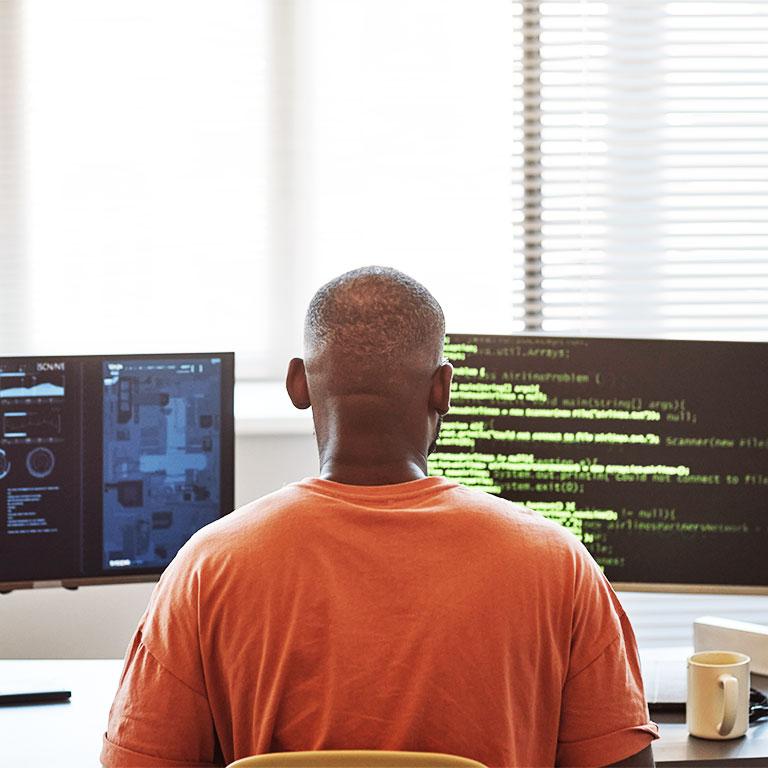 man sitting in front of monitor with code