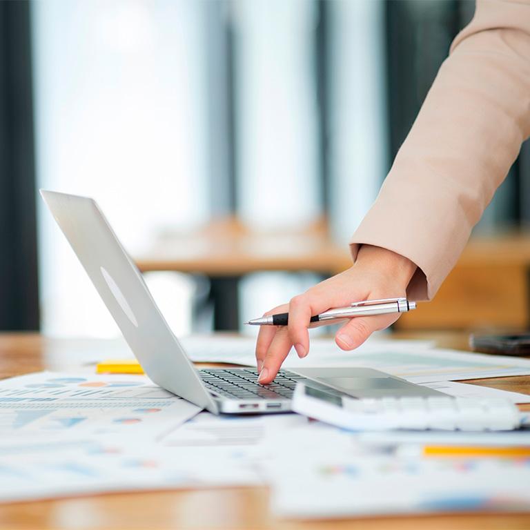 hand holding pen and touching laptop keyboard