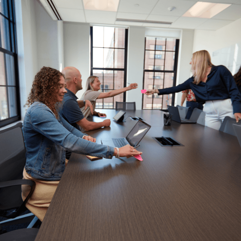 Coworkers at a table passing each other sticky notes