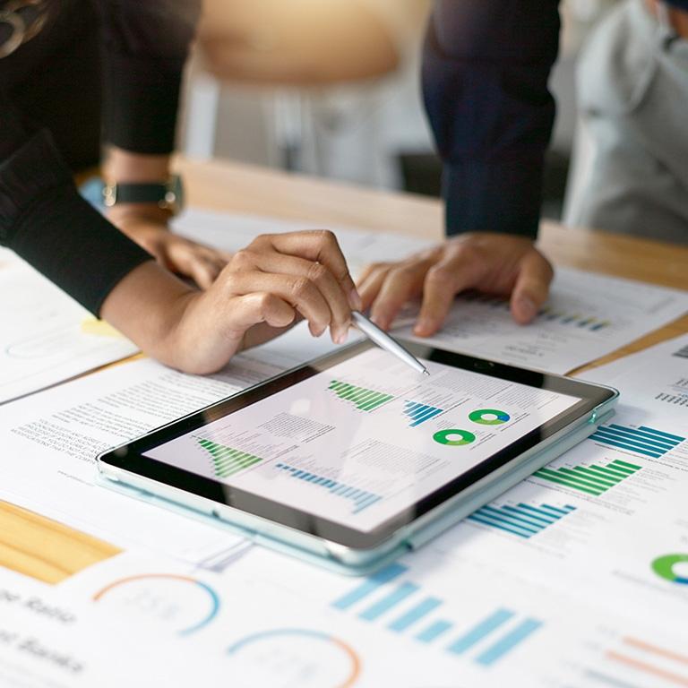 Two people using a tablet with charts and graphs on it