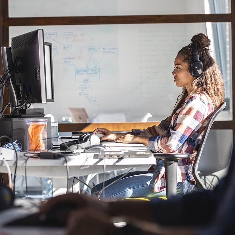 women working at her desk and wearing headphones