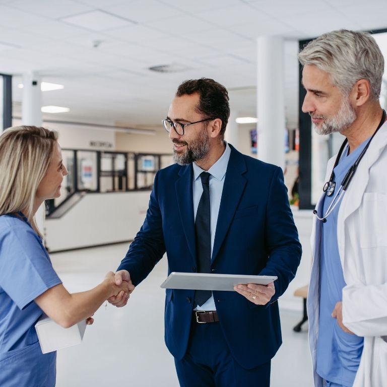 man in suit shaking hands with healthcare workers