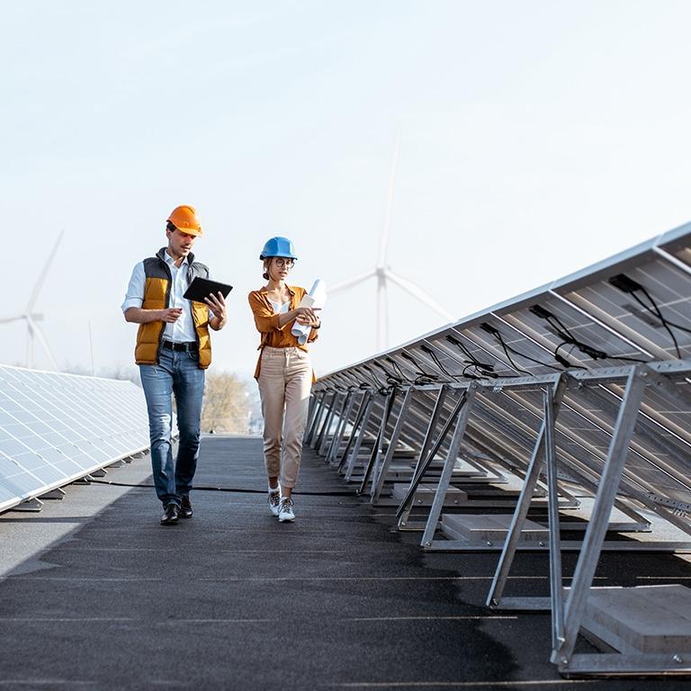 people with hardhats walking next to solar panels