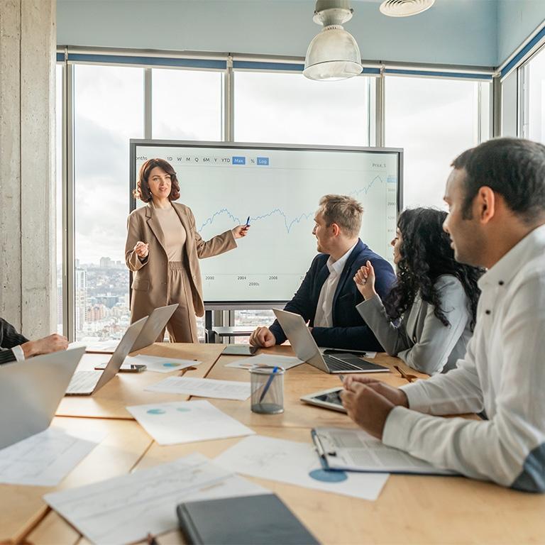 business people around a conference table with a screen with charts