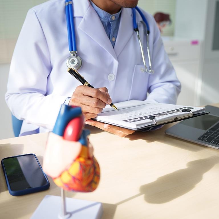 person in lab coat writing on clipboard