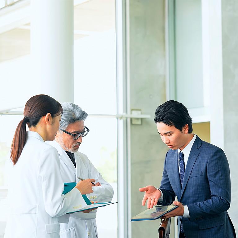 man in suit talking to healthcare workers