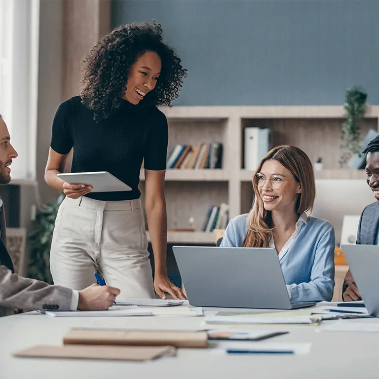 people gathered around a table with laptops and tablets