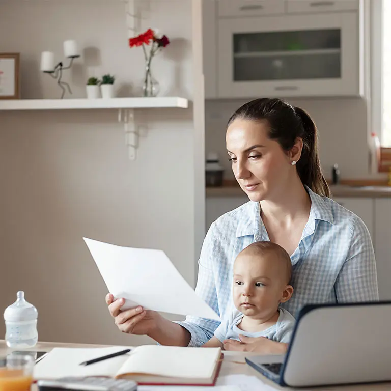 woman with a baby on her lap looking over bills and documents