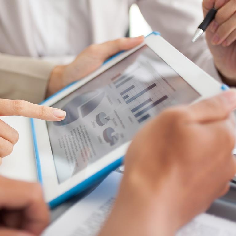 hands pointing at a tablet with charts and graphs