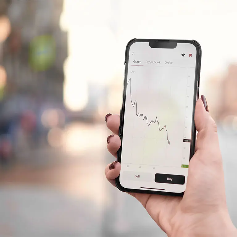 woman holding a phone and the screen shows a stock chart