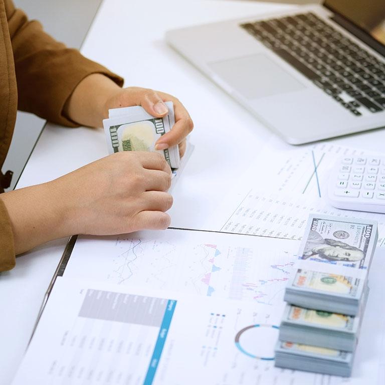 woman counting a roll of cash in a desk setting