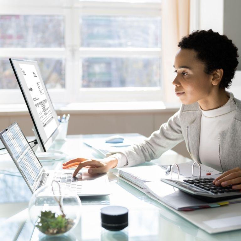 person at desk with laptop and monitor