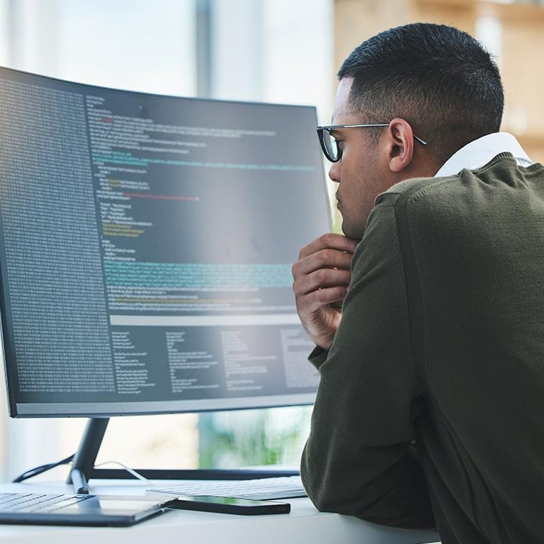 person looking at code on a large monitor