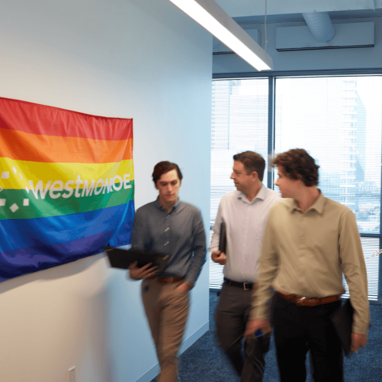 Three men walking past a West Monroe Pride flag