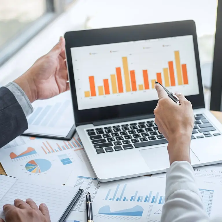two people analyzing a bar chart on a computer screen