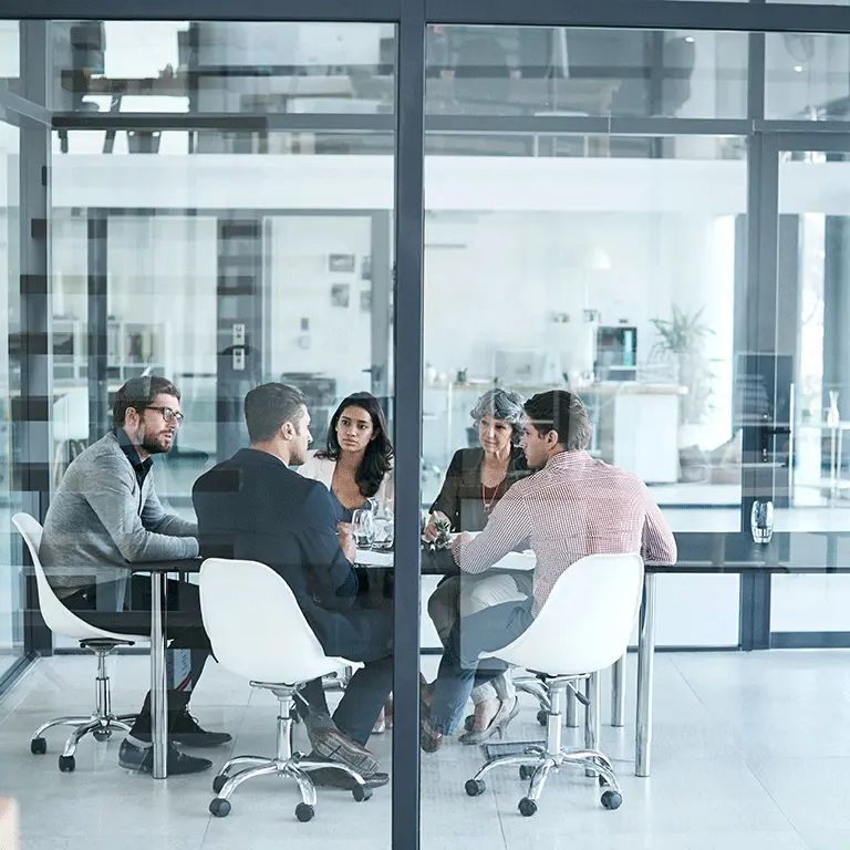 co-workers talking around a table viewed through a window