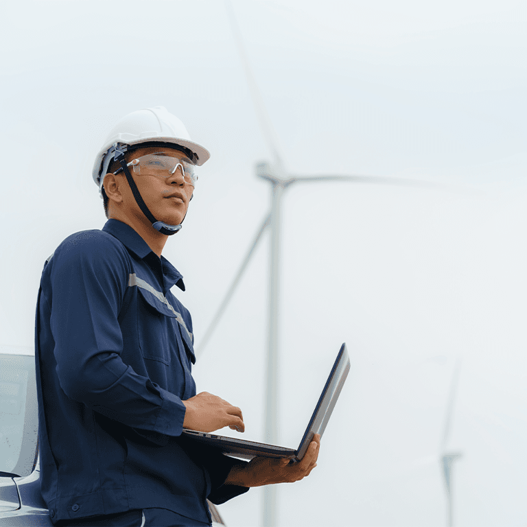 man with laptop in front of wind turbines