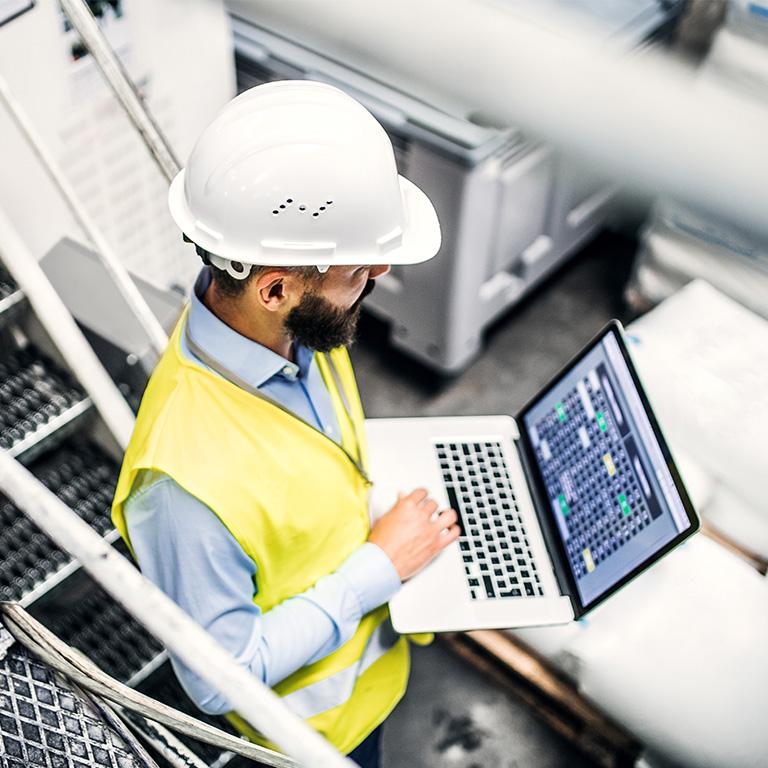 person in hardhat using a laptop