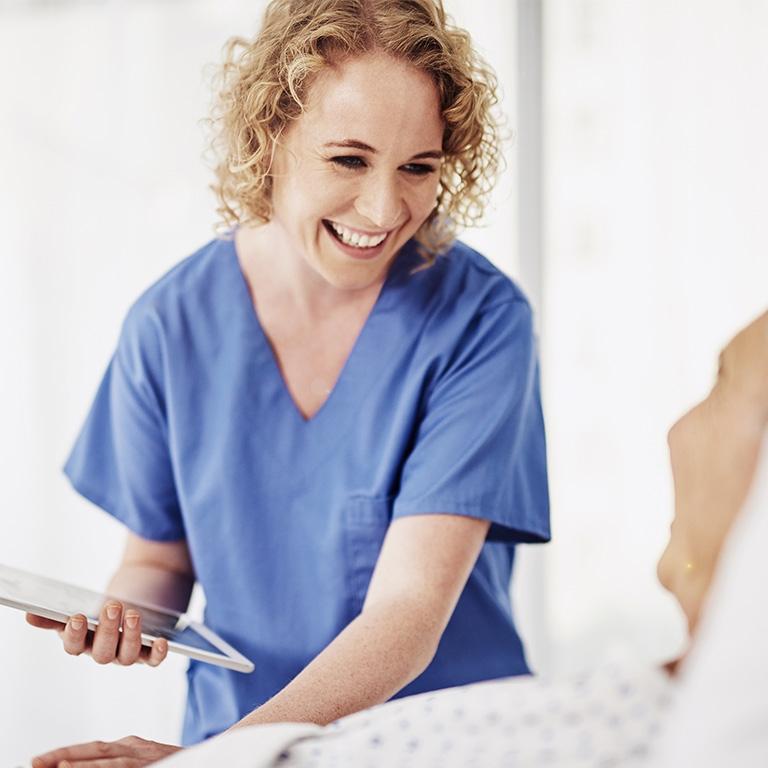woman in scrubs holding a tablet