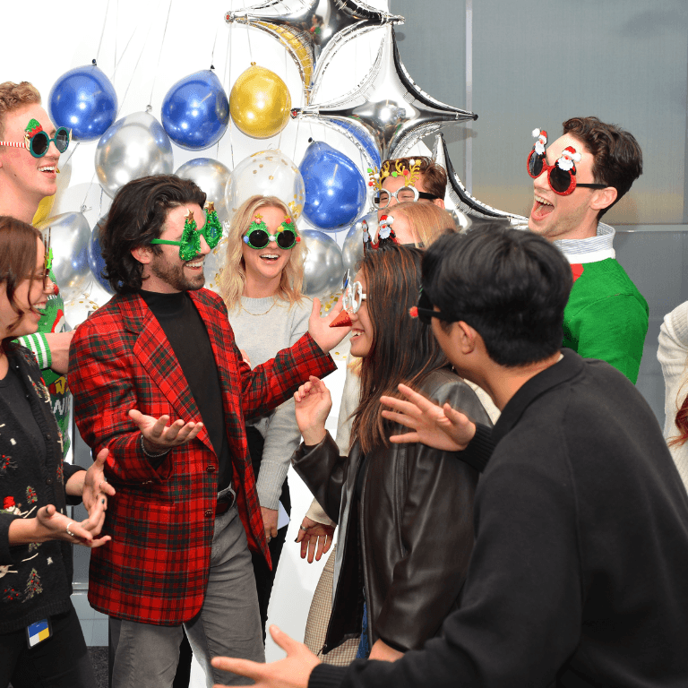 Group of people wearing festive holiday sunglasses laughing