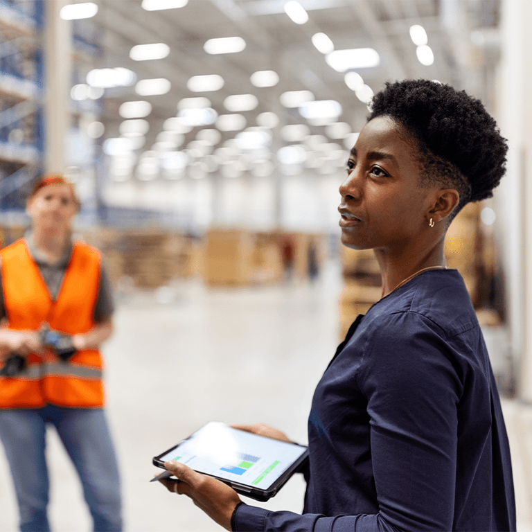 person taking notes on a tablet in a warehouse