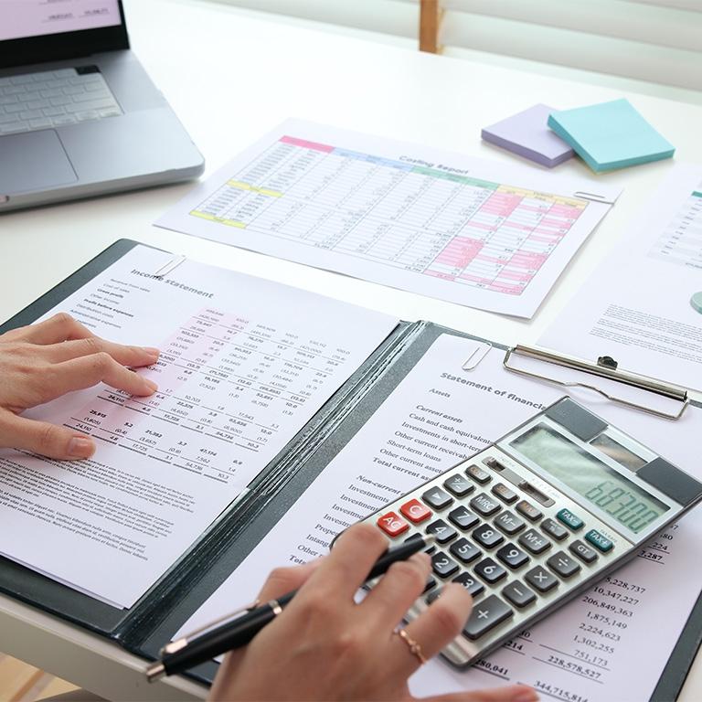 hands on a calculator and invoice sheets