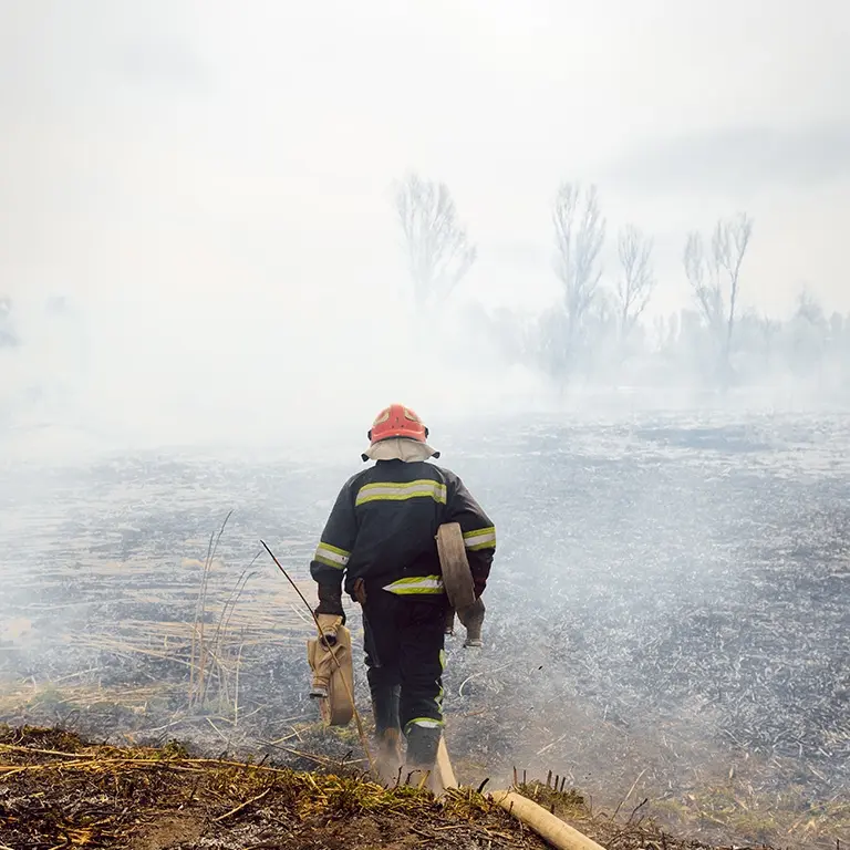 firefighter standing before smoke